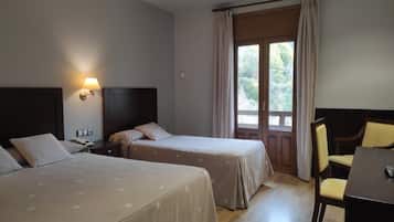 Habitación de hotel con dos camas, un escritorio y una silla.