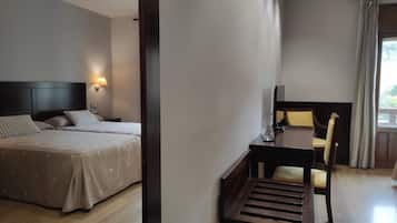 A hotel room with a bed, bedside table, lamp, and a desk with a chair.