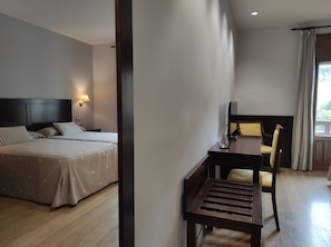 Una habitación de hotel con cama, mesita de noche, lámpara y escritorio con silla.