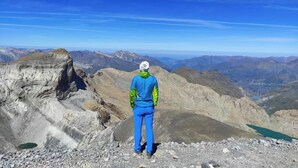 A person standing on a rocky mountain peak with a panoramic view of the surrounding landscape. - Snö Bielsa (Bielsa)