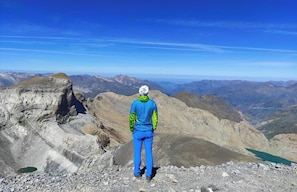 A person standing on a rocky mountain peak with a panoramic view of the surrounding landscape. - Snö Bielsa (Bielsa)