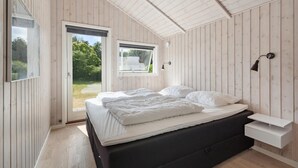 A bedroom with a bed, a bedside table, a window, and a view of greenery outside. - 3 bedroom nice home in Broager (Broager)