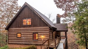 Una baita rustica con un portico in legno e una scala che conduce a un terrazzo.