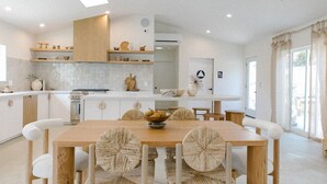 A spacious kitchen with a central island, wooden chairs with woven seats, and a dining table. - Yara Hotel (Palm Springs)