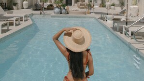 A pool area with lounge chairs and umbrellas, surrounded by palm trees. - Yara Hotel (Palm Springs)