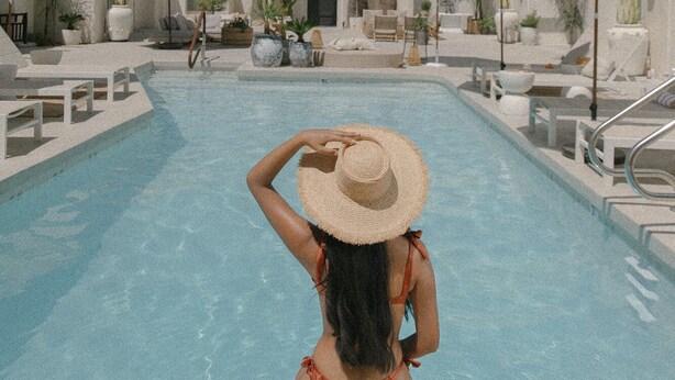 A pool area with lounge chairs and umbrellas, surrounded by palm trees. - Yara Hotel (Palm Springs)