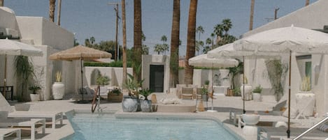 Una piscina al aire libre, camas de piscina gratis, sombrillas