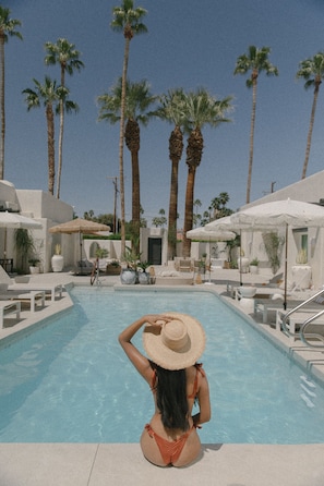 A pool area with lounge chairs and umbrellas, surrounded by palm trees. - Yara Hotel (Palm Springs)