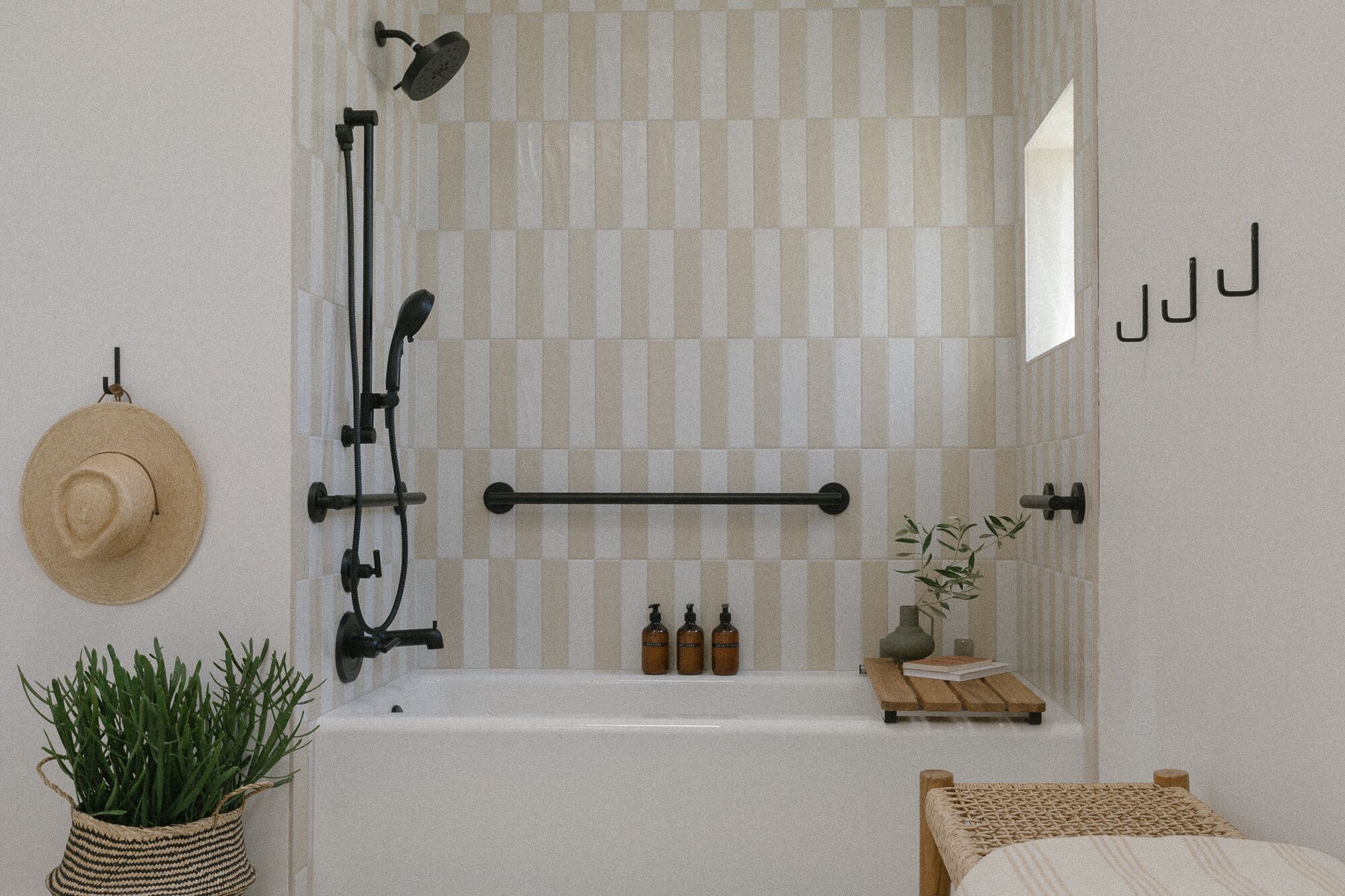 A bathroom with a checkered shower curtain, a towel rack, a hat, and toiletries on the sink.