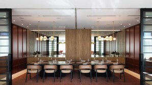A modern dining area with a long table, multiple chairs, and pendant lighting. - Pullman Sydney Penrith (Penrith)