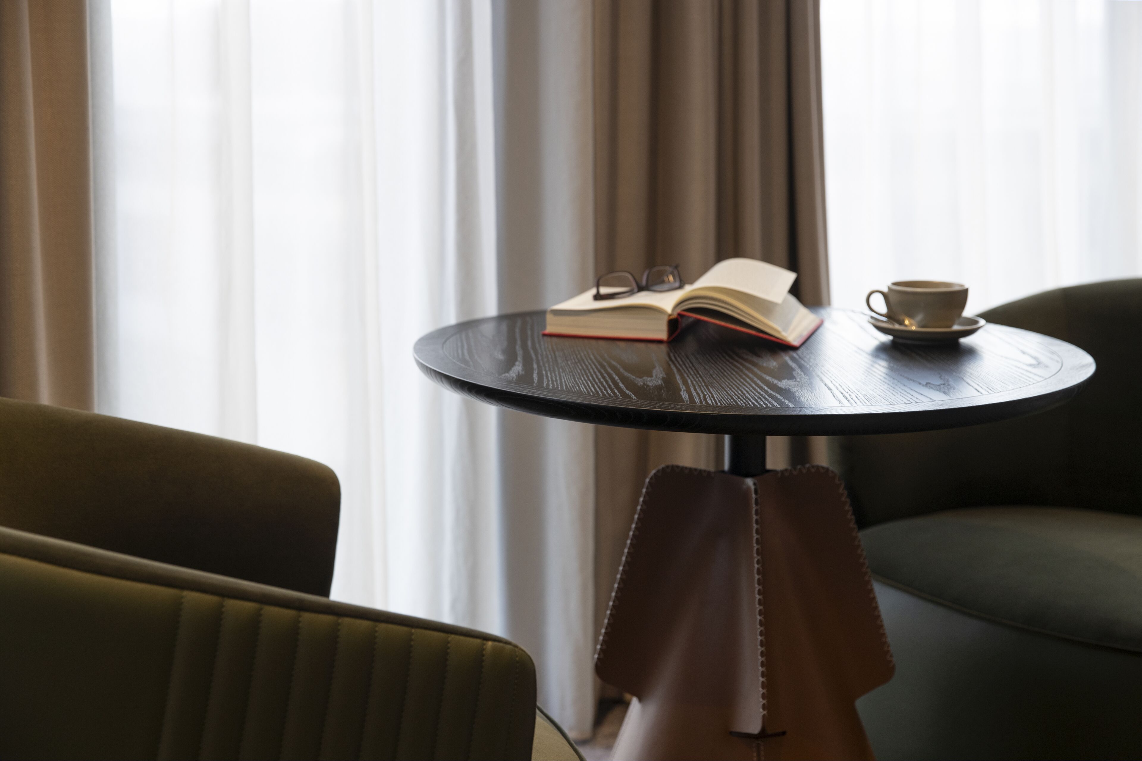 Une table ronde avec un livre, des lunettes et une tasse.