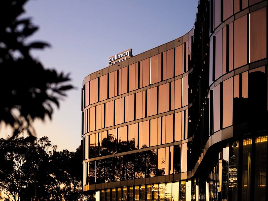 A modern hotel building with a reflective glass facade and a sign reading "Pullman Hotels."