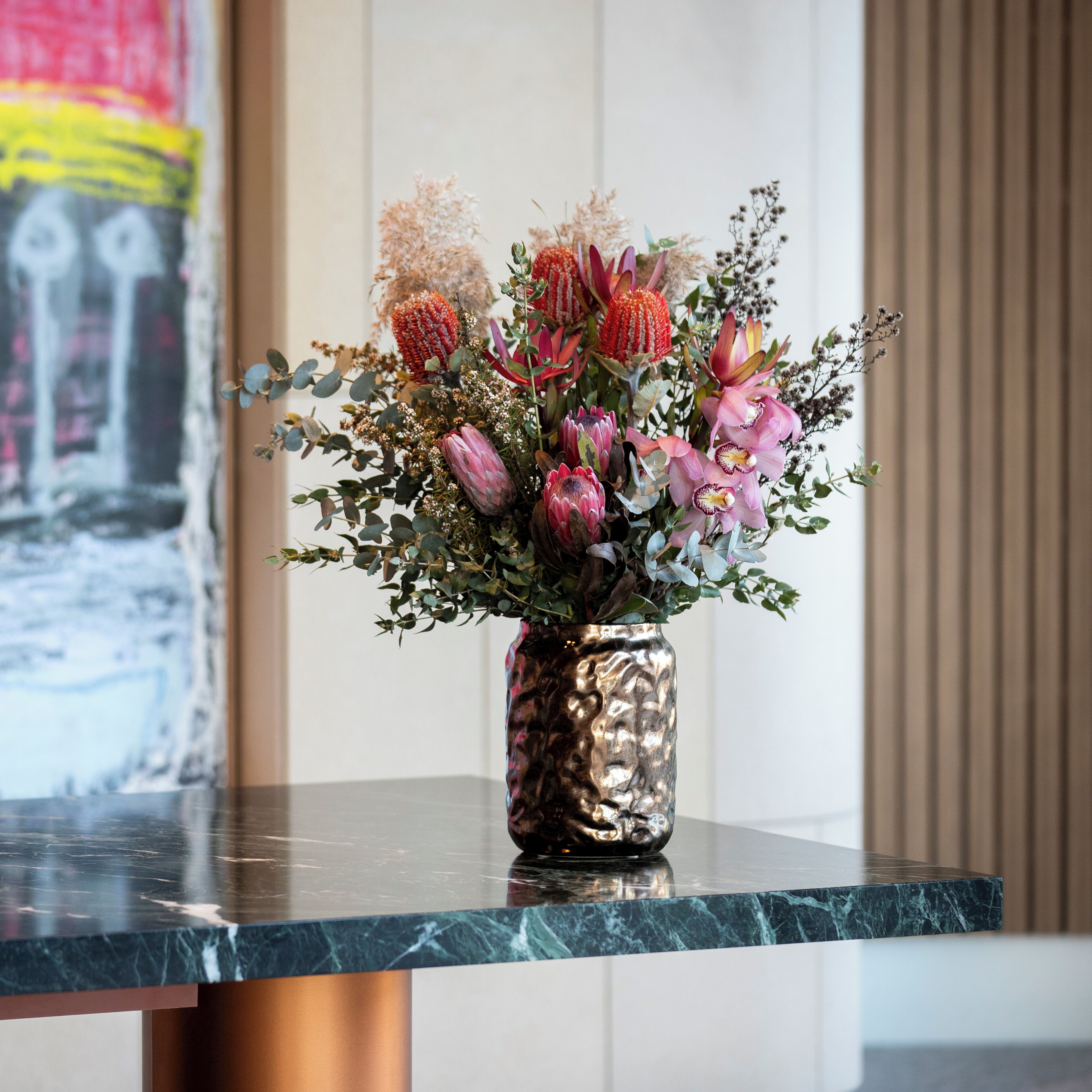 A vase with a floral arrangement on a marble countertop.
