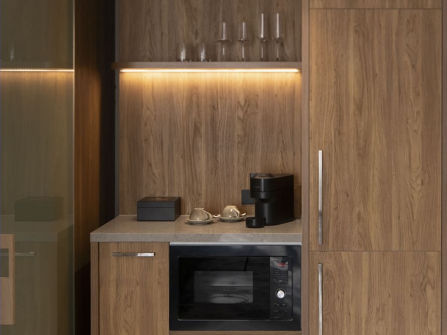 A modern kitchen with wooden cabinetry, a built-in oven, and a coffee maker on the countertop.