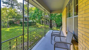 A covered balcony with metal railings, wicker chairs, and a view of a green garden and trees. - Ole Miss Spirit Lives 2 Mi From Campus (Oxford)