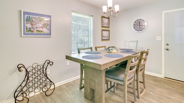 A dining area with a wooden table, chairs, a chandelier, framed pictures, and a window with blinds. - Ole Miss Spirit Lives 2 Mi From Campus (Oxford)
