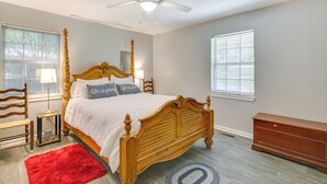 A bedroom with a wooden four-poster bed, a red rug, a nightstand, a dresser, and a ceiling fan. - Ole Miss Spirit Lives 2 Mi From Campus (Oxford)