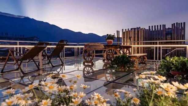 A rooftop terrace with lounge chairs, a wooden table, and potted plants. - Private running bar post Dali ancient shop (Dali City)