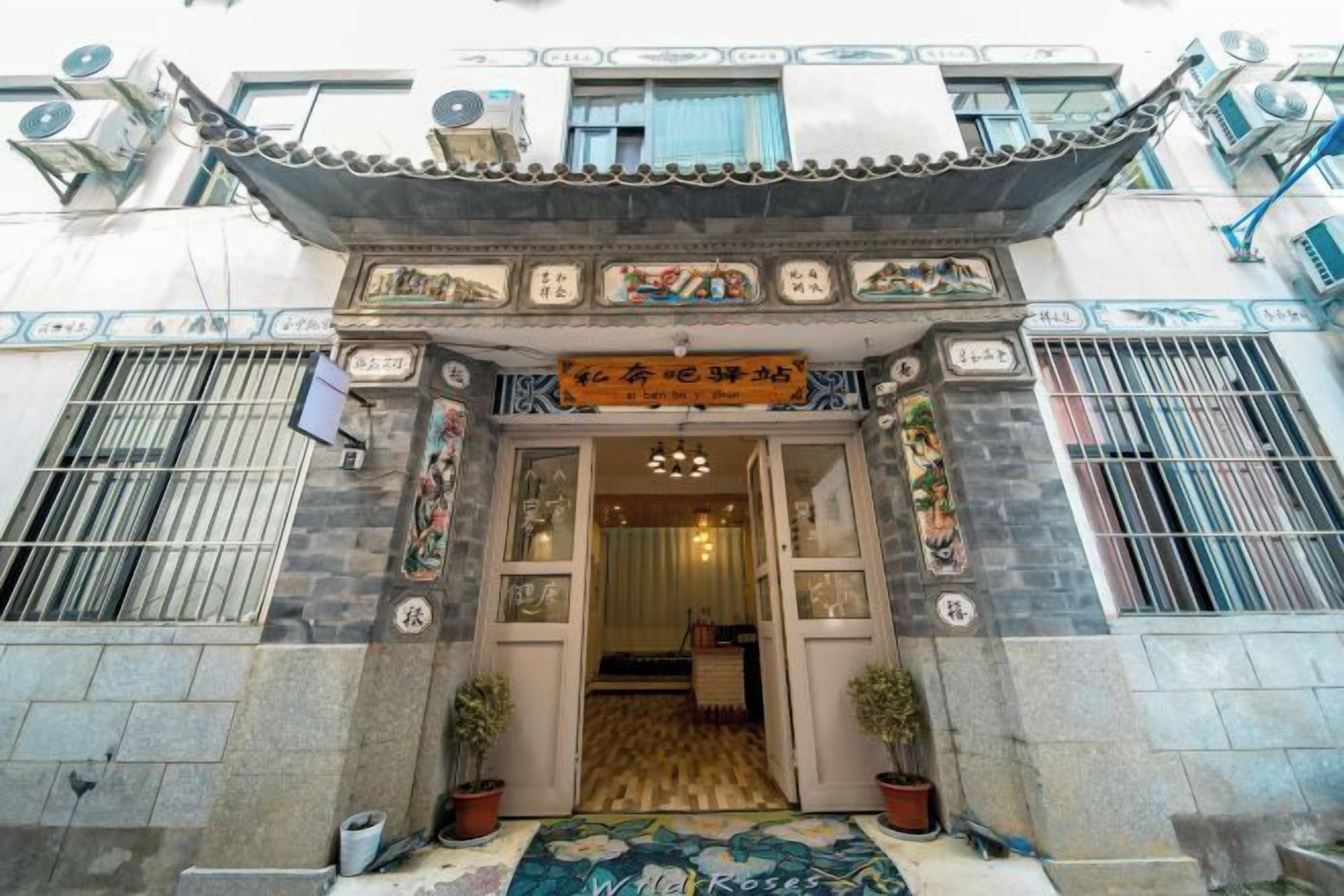 Un edificio tradicional con vestíbulo de baldosas, plantas en macetas y un letrero con caracteres chinos.
