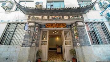 Un edificio tradicional con vestíbulo de baldosas, plantas en macetas y un letrero con caracteres chinos.