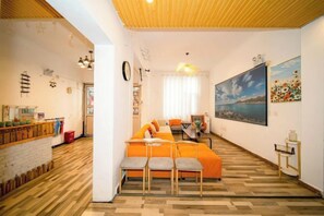 A living room with a sofa, chairs, a dining table, and artwork on the walls. - Private running bar post Dali ancient shop (Dali City)