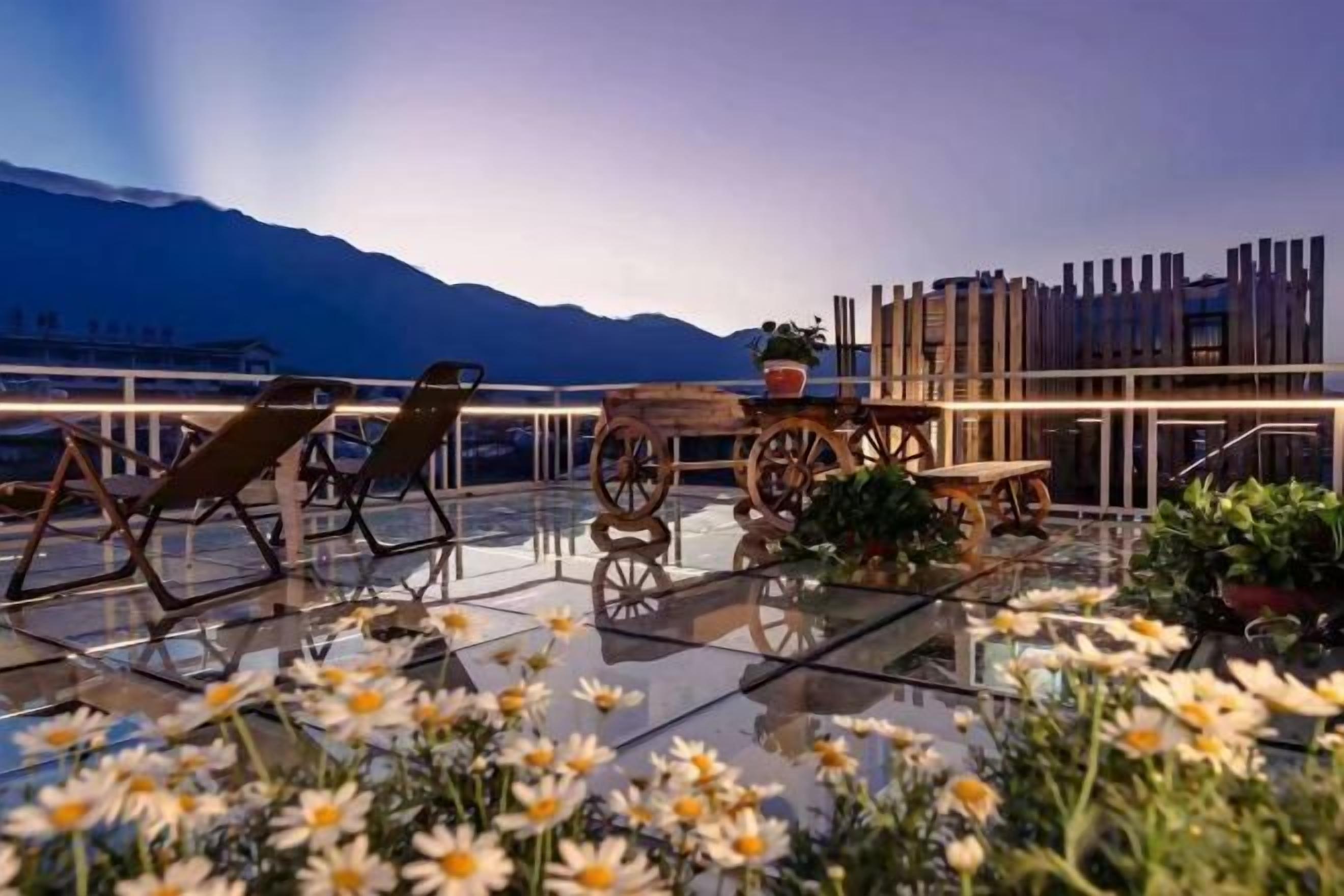 A terrace with a glass table, chairs, and potted plants.