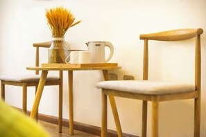 A wooden table with a white mug and a glass container with wheat stalks.