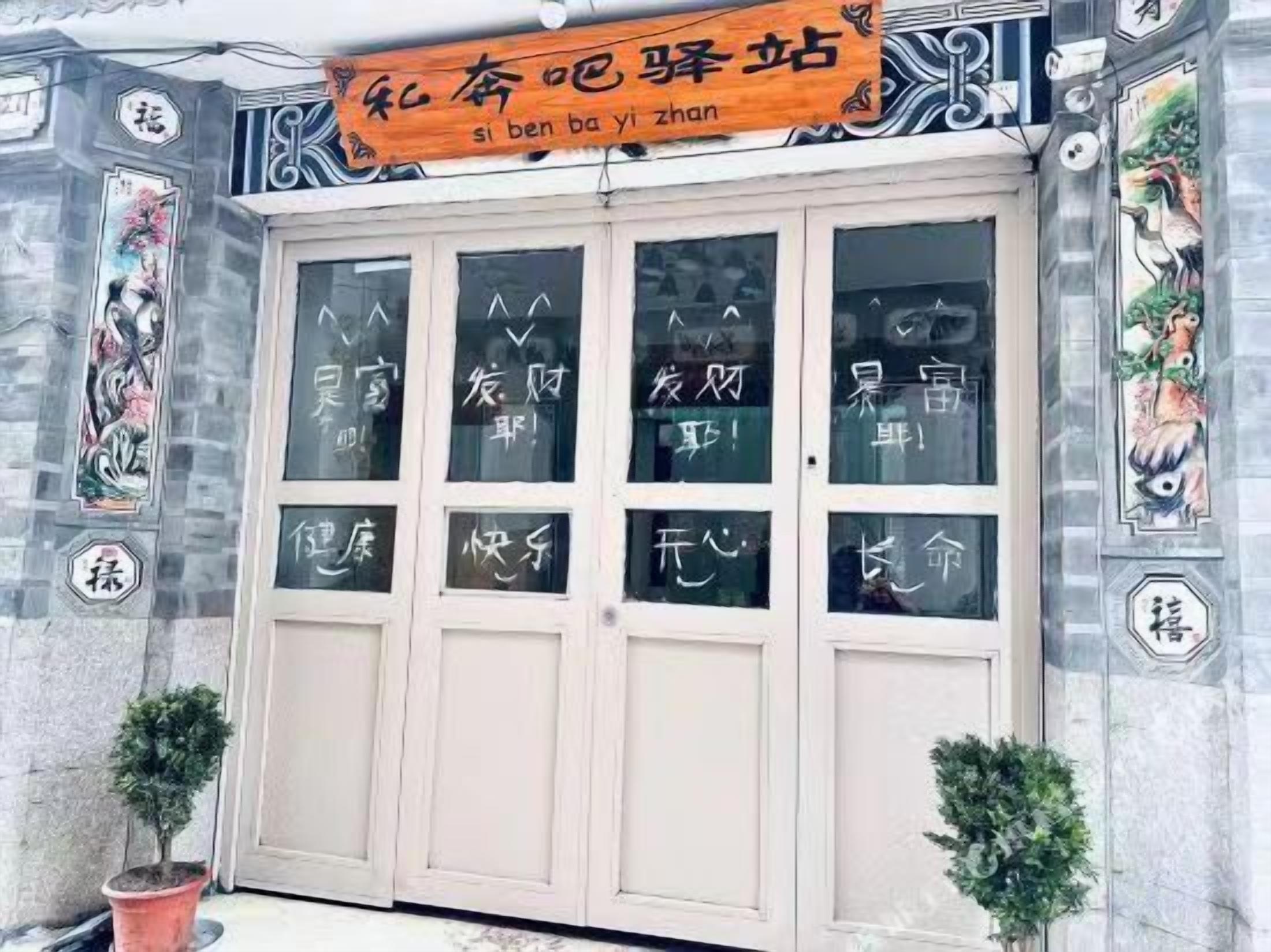 A building facade with a large entrance door, decorative wall panels, and a sign above the door.