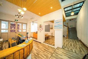 A reception area with a wooden desk, a seating area, and a staircase leading to an upper level. - Private running bar post Dali ancient shop (Dali City)