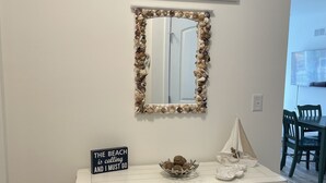 A white console table with a decorative mirror, a sign reading "The Beach is calling and I must go", and a small sailboat model. - Beautiful Family Beach Retreat-Pool, Marina, and minutes to the beach. (Lewes)