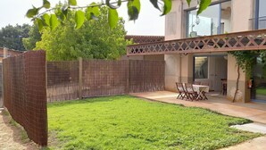 Een achtertuin met houten omheining, gazon en een tafel met stoelen.
