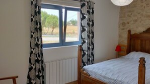 Een slaapkamer met een houten bed, een raam met gordijnen, een radiator en een rode lamp.
