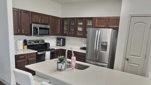 A modern kitchen with a central island, stainless steel appliances, and brown cabinetry.