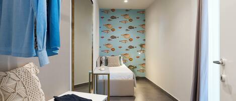 A narrow hallway with a bed, a small table, and a bench.
