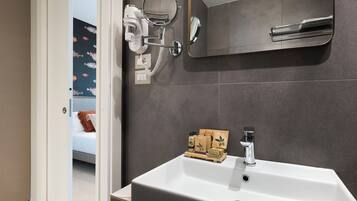 Un baño con lavamanos blanco, un espejo y un perchero para toallas.