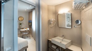 A modern bathroom with a sink, mirror, towel rack, and shower. - Belduomo (Taormina)