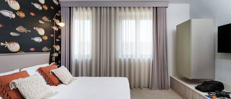 Una habitación de hotel con cama, televisor, armario y cortinas.