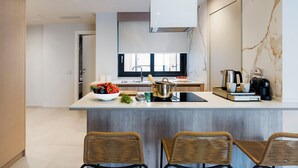 A modern kitchen with a central island, bar stools, a window, and a built-in oven. - Belduomo (Taormina)
