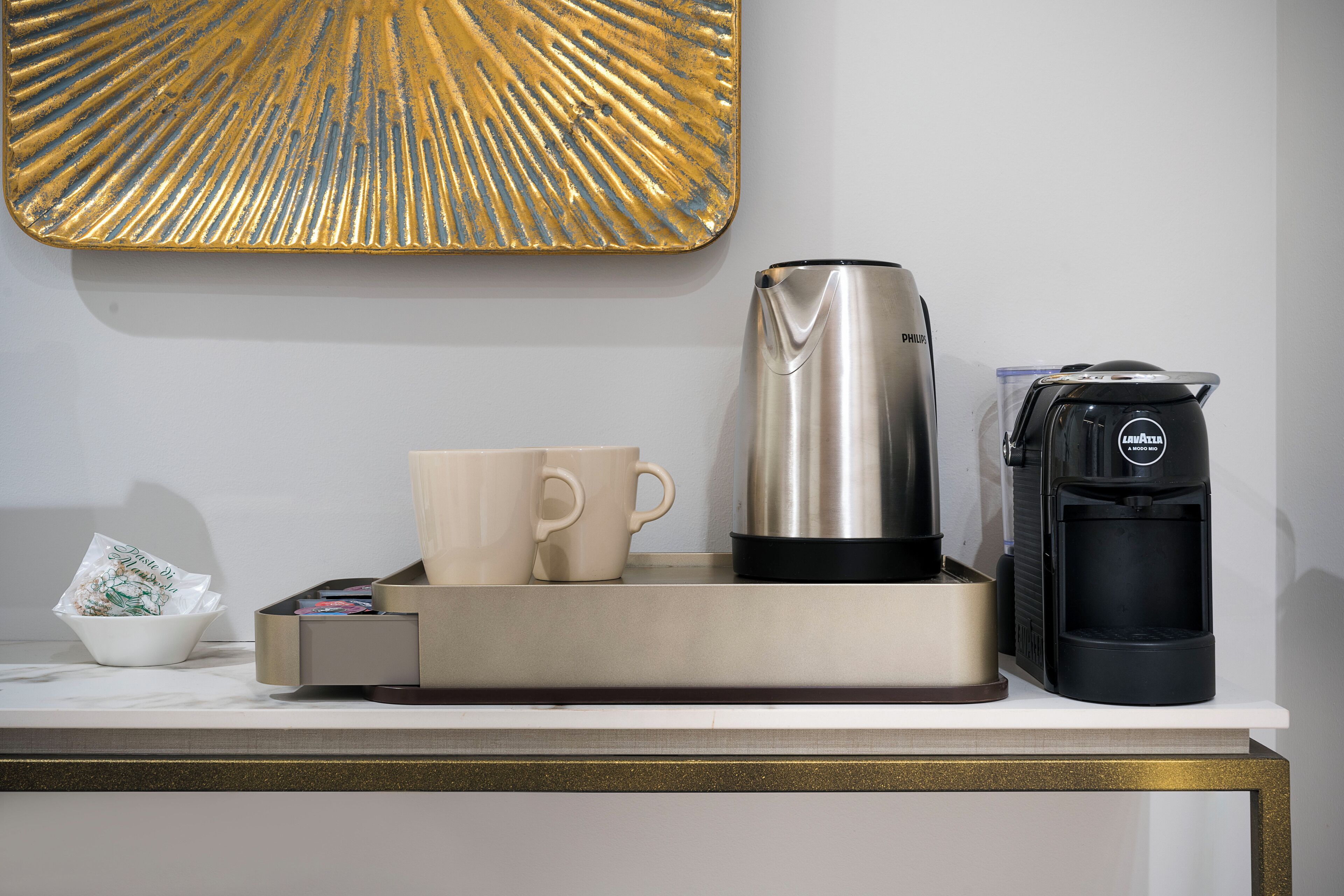 A coffee station with a coffee maker, a cup, and a coffee pod dispenser on a counter.