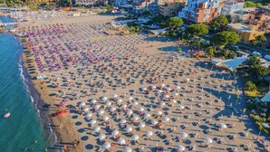 An aerial view of a beach with numerous umbrellas and sun loungers, indicating a large capacity for guests. - Belduomo (Taormina)
