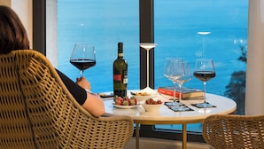 A person seated at a table with a view of the sea, a bottle of wine, and a book. - Belduomo (Taormina)