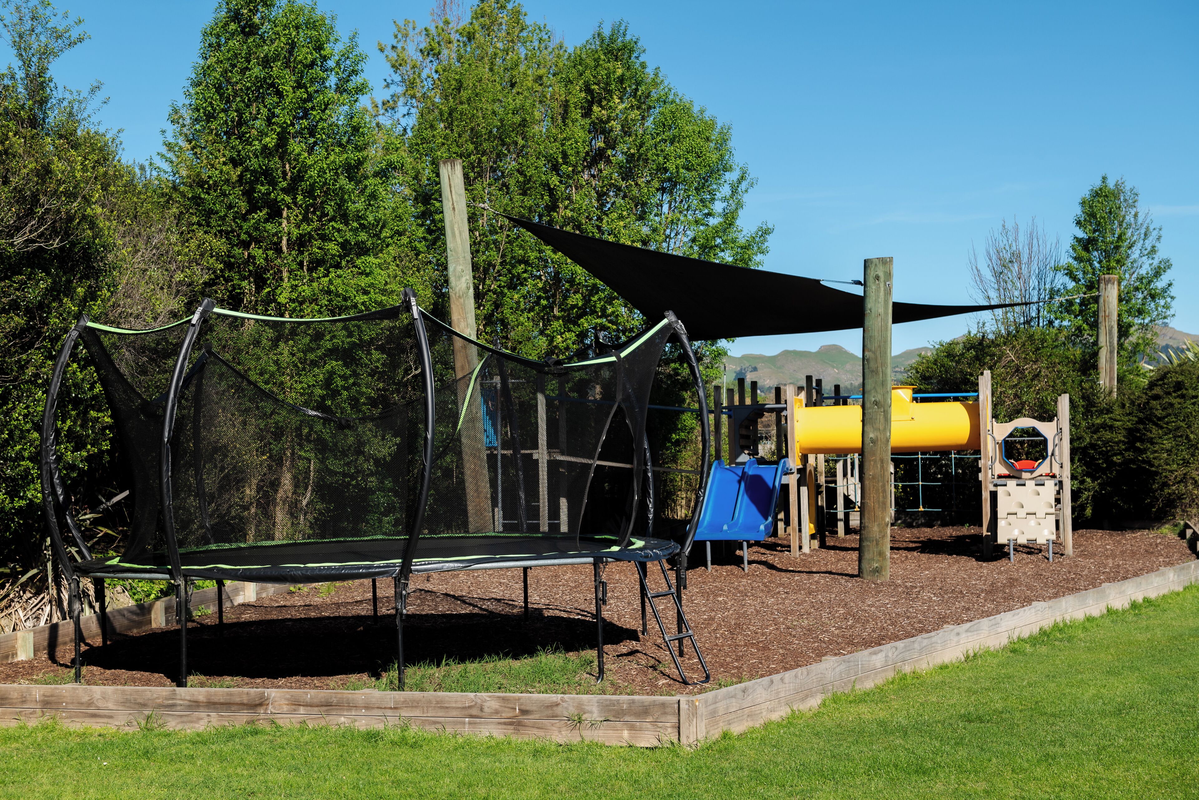 A playground with a trampoline, a slide, and a climbing structure.