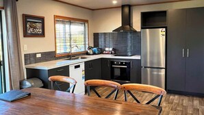 A modern kitchen with a wooden dining table, chairs, and built-in appliances. - Havelock North Holiday Park  (Havelock North)