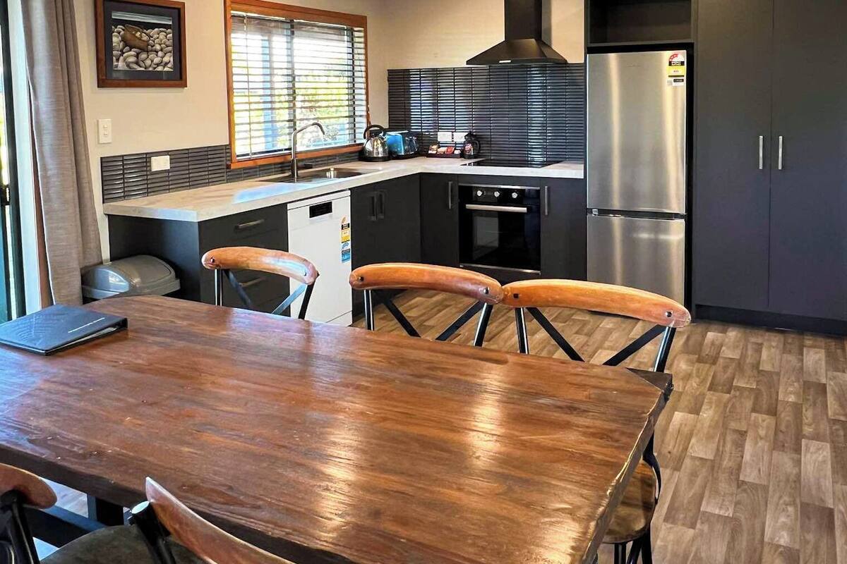 Een moderne keuken met een houten eettafel, stoelen en inbouwapparatuur.