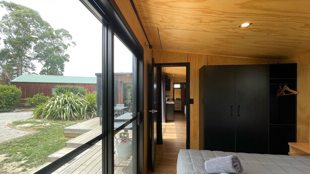A modern bedroom with a large window, a bed, and a wardrobe. - Havelock North Holiday Park  (Havelock North)
