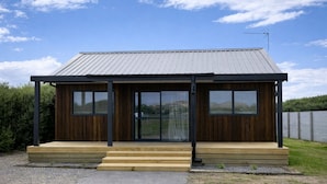 A modern house with a metal roof, wooden exterior, and large sliding glass doors. - Havelock North Holiday Park  (Havelock North)
