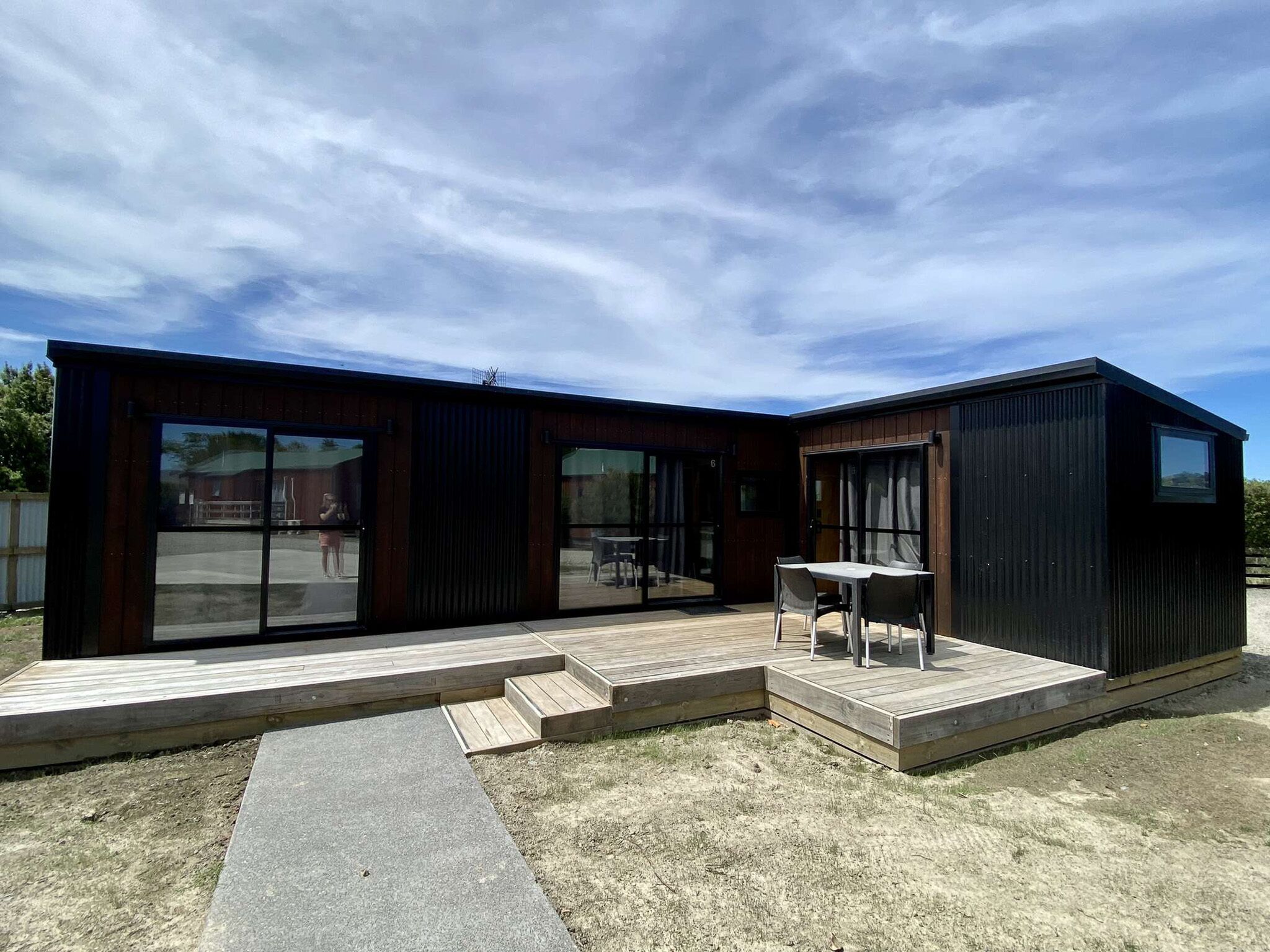 A modern two-story house with large glass doors and a patio area.