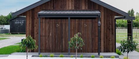 Ein modernes Gebäude mit Holzfassade, großen Garagentüren und einem Schotterweg mit kleinen Pflanzen.