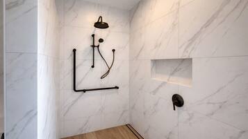 A modern shower with a handheld showerhead, a wall-mounted control panel, and a wooden floor.