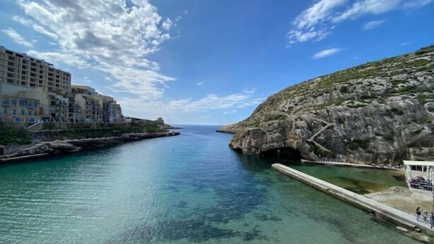 Une ville côtière bordée d’une mer d’un bleu profond, de falaises rocheuses et de bâtiments qui s’alignent le long du rivage.